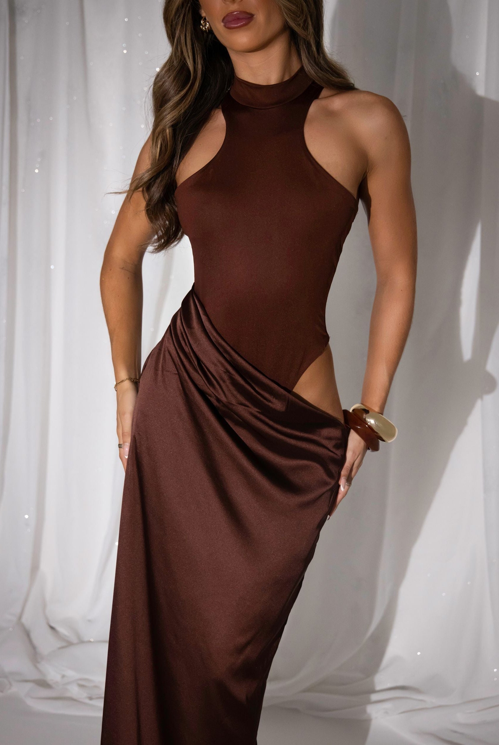 Women's brown maxi dress with built in brown bodysuit and racer style neckline and satin skirt starting at waistline. Cut out detail on the thigh and maxi length skirt.